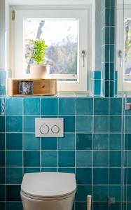 een blauw betegelde badkamer met een toilet en een raam bij Homely in Heidenheim an der Brenz