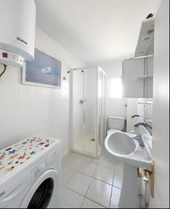 y baño blanco con lavabo y lavadora. en Apartamentos Formentera Copacabana 18, en Es Pujols