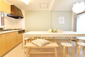 東京的住宿－アンドステイ羽田4丁目，厨房配有桌子、一些椅子、桌子和柜台。