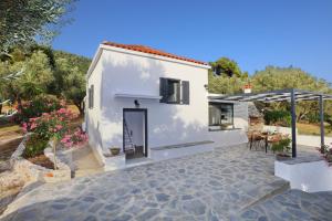 a white house with a patio and an umbrella at Villa John's Skopelos Stafilos in Skopelos Town