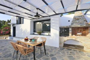 a patio with a table and a brick fireplace at Villa John's Skopelos Stafilos in Skopelos Town