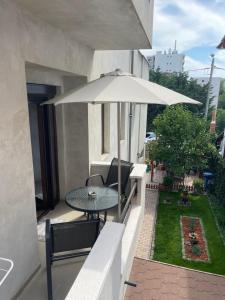 eine Terrasse mit einem Tisch und einem Sonnenschirm auf dem Balkon in der Unterkunft Vila AlMare in Eforie Nord