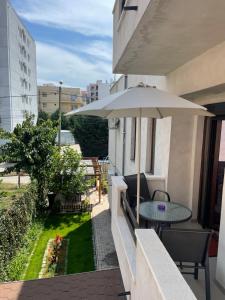 eine Terrasse mit einem Tisch und einem Sonnenschirm auf dem Balkon in der Unterkunft Vila AlMare in Eforie Nord