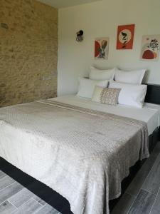a large bed with white sheets and paintings on the wall at Domaine de Lascaux in Montignac