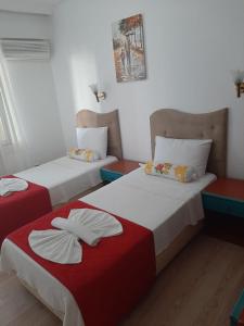 two beds in a small room with red and white at Sevo Hotel in Ayvalık