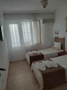 a bedroom with three beds and two windows at Sevo Hotel in Ayvalık