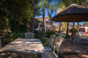 uma mesa e cadeiras e um guarda-sol num pátio em Gabus Safari Lodge em Otavi