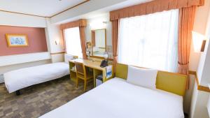 a hotel room with two beds and a desk at Toyoko Inn Oyama eki Higashi guchi No 1 in Oyama