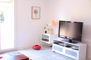 un soggiorno con TV a schermo piatto su un centro di intrattenimento bianco di Gîte des Laquets a Sérignan-du-Comtat