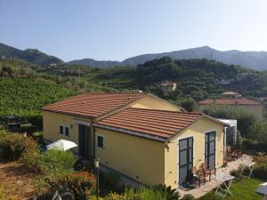 a yellow house on a hill with mountains in the background at Agriturismo La Collina Verde in Levanto