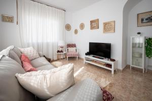 ein Wohnzimmer mit einem weißen Sofa und einem TV in der Unterkunft AT101 Baix a Mar in Torredembarra