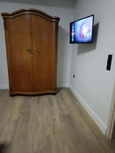 duża drewniana szafka w pokoju z telewizorem z płaskim ekranem w obiekcie By The Lake w mieście Kastoria