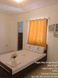 een slaapkamer met een bed met een vaas met bloemen erop bij WJV INN MARIBAG0 in Maribago
