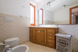 bagno con servizi igienici, lavandino e specchio di Appartamento Oleandro a Città di Lipari