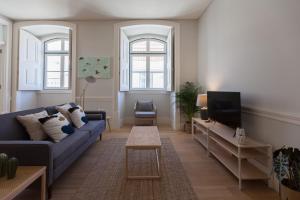 ein Wohnzimmer mit einem blauen Sofa und einem TV in der Unterkunft FLH Praça Rossio Bright Apartment in Lissabon