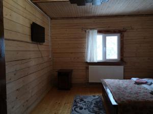 a bedroom with wooden walls and a bed and a window at ДАН in Dragobrat