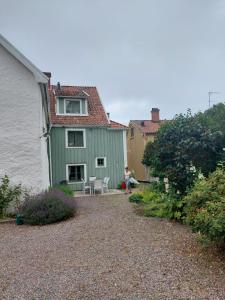 una mujer sentada frente a una casa verde en Vadstena semesterlägenhet en Vadstena