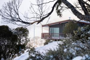 uma casa com varanda na neve em Guthega Inn em Perisher Valley