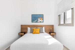 a bedroom with a large white bed with yellow pillows at Mate TLV PORT - By HOMY in Tel Aviv
