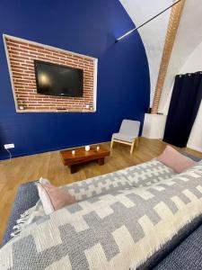 Habitación azul con cama y TV en la pared en Les voûtes de Mila en Montauban
