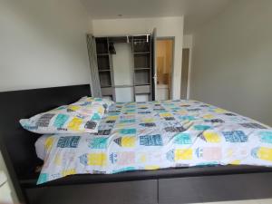 a bed with a comforter and pillows in a bedroom at Résidence de la gare, chambre meublée in Longjumeau