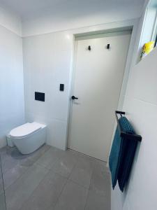 La salle de bains blanche est pourvue de toilettes et d'une porte. dans l'établissement Emu Retreat B&B, à Tailem Bend
