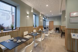 a dining room with tables and white chairs at Plaza de la Luz Cádiz in Cádiz