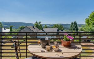 a wooden table with wine glasses and flowers on a balcony at Le chalet de pépère in Stavelot