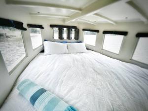 ein großes Bett in der Mitte eines Zimmers mit Fenstern in der Unterkunft Baby Blue Houseboat in Port Edward