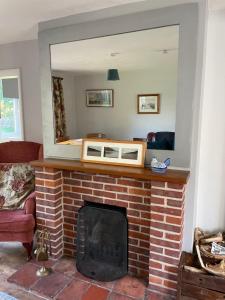a fireplace with a mirror on top of it at Betty's Cottage - Traditional Norfolk Farm Cottage in Swafield