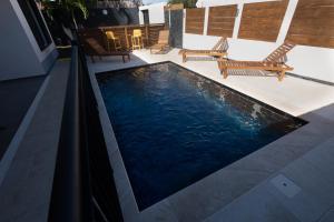 een zwembad op een patio met stoelen en tafels bij Villa Cap Noir piscine chauffée avril à octobre in Saint-Joseph