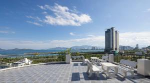 un patio con sillas blancas y vistas al agua en MYDO Condotel en Nha Trang