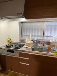 a kitchen with a sink and a stove and a window at ABC accommodation in Osaka