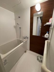 een badkamer met een bad, een wastafel en een spiegel bij ABC accommodation in Osaka