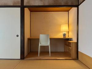 a room with a chair and a desk with a lamp at AKUNOURA HUIS in Nagasaki
