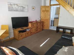 a living room with a flat screen tv on a wooden cabinet at Dawlish Holiday Apartment in Dawlish