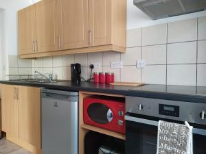 a kitchen with a red microwave on a counter at Dawlish Holiday Apartment in Dawlish