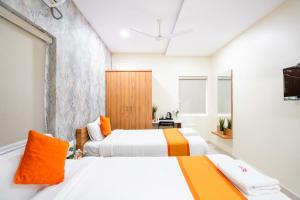 2 camas en una habitación con blanco y naranja en Iris at Nest, en Hyderabad