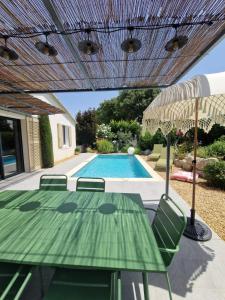 um pátio com uma mesa e cadeiras e uma piscina em Magnifique Villa avec Piscine en Provence em Verquières