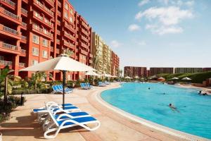 a swimming pool with lounge chairs and an umbrella at Porto Golf Marina Alamein in El Alamein