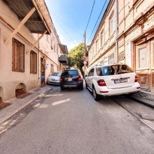 deux voitures garées dans une rue à côté des bâtiments dans l'établissement Hostel Pirosmani, à Tbilissi