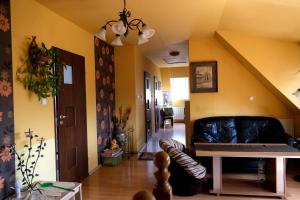 salon z żółtymi ścianami i czarną skórzaną kanapą w obiekcie Gospodarstwo Agroturystyczne Ćmilówka 
