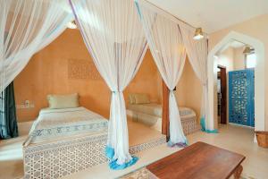 a bedroom with a bed with curtains and a table at Kendwa Rocks Hotel in Kendwa