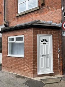 a brick building with a white door and two windows at Swinefleet Maisonettes. Airy, Modern & Chic! in Goole