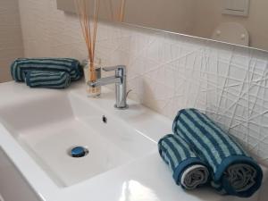 un lavandino in bagno con un asciugamano blu poggiato sopra di Luxury home near the Beach private parking space ad Alghero