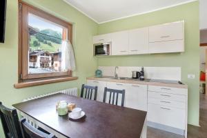 a small kitchen with a table and a window at Mele Baitel li Pigna in Livigno