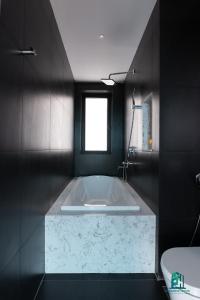 een wit bad in een zwarte badkamer met een raam bij Luxe Paradise Residence 5 Tu Hoa in Hanoi