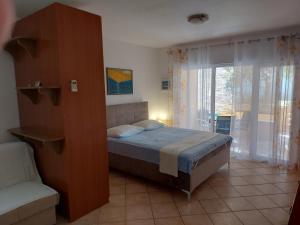 a bedroom with a bed and a chair and a window at Apartment Vivoda in Štinjan