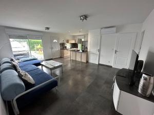 uma sala de estar com um sofá azul e uma cozinha em La VILLA DES PINS Maison Standing 7 pers Terre et Mer em Brach