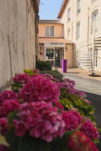 un mazzo di fiori rosa di fronte a un edificio di Hôtel Le Cheval Blanc a Saint-Maixent-l'École